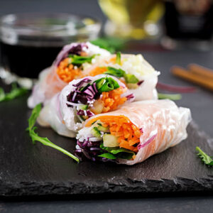 Vegetarian vietnamese spring rolls with spicy sauce, carrot, cucumber, red cabbage and rice noodle. Vegan food. Tasty meal.