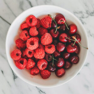 Photo of raspberries and cherries in a prep bowl for baking.